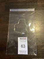 Sterling silver 925 chain with heart-shaped blue stone pendant laid on dark wood surface in a clear plastic bag showing lot number 63.