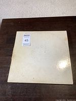 Front cover of The Beatles The White Album gatefold vinyl record showing white cover with faint embossed text and wear.