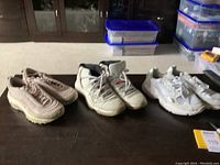 Trio of sneakers: Pink Nike Air Max 97, white Air Jordan 11, and white adidas shoes, displayed side by side.