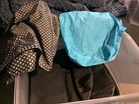 Photo of various bags including a black and beige patterned fabric bag, a blue drawstring nylon bag, and large white fabric bag with colorful text.