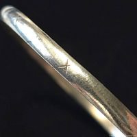 Close-up photo showing the etched cross line detail on the sterling silver bangle surface.