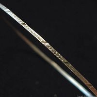 Close-up image showing the engraved textured pattern on the sterling silver bangle surface.