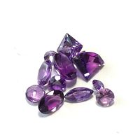 Loose faceted amethyst gemstones on a white background showing various cuts and purple shades.