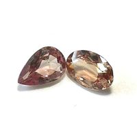 Faceted pear-shaped and oval-shaped color changing garnet gemstones showing a reddish-brown and light brown tone.