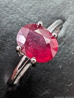 Close-up front view of the oval cut natural ruby gemstone set in a sterling silver band ring.