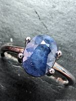 Close-up front view of the sterling silver ring with an oval blue sapphire showing facets and some inclusions.