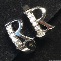 Close-up of front view of two sterling silver hoop earrings with V-shaped cubic zirconia detailing.