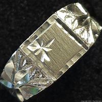 Close-up front view of the sterling silver ring showing the rectangular top with an engraved star and floral details on the sides.