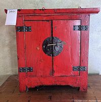 Front view of red lacquer cabinet showing doors, lock plate and hinges