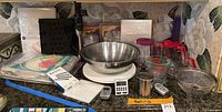 Overview of assorted kitchen prep items including mixing bowl on scale, paper goods, spatula, immersion blender attachment