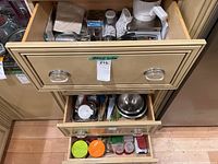 View of partially open drawers revealing food containers with colorful lids, bowls, additional utensils, and small kitchen tools.