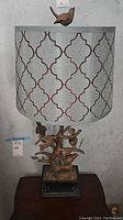 Full view of lamp showing sculpted tree base with bird figurines and patterned lampshade.