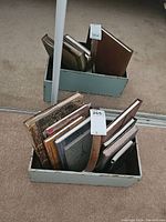 Decorative box holding books and journals standing on carpet near mirrored closet doors.