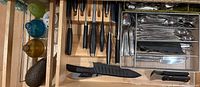 Drawer with J.A. Henckels knife block, mixed black-handled knives, stainless mesh silverware organizer with forks, spoons and steak knives, plus six glass pour bottles