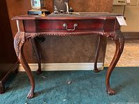Front view of the Butler Specialty Company hall table showing the single drawer with brass handle and carved cabriole legs ending in claw feet.
