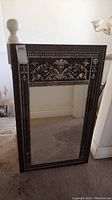 Full view of the rectangular wall mirror with dark wood frame and decorative light floral inlay on top and sides