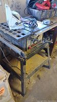 Front three-quarter view of table saw on stand with power cord and accessories on top