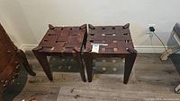 Pair of woven leather seat stools with wooden frames, viewed from above and the side.