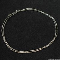 Sterling silver chain necklace arranged in a circular shape on a black background, showing overall length and chain links.