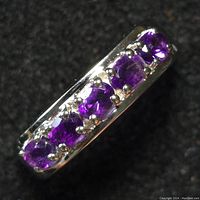 Close-up photo of the silver ring with five oval purple amethyst stones set in a row on a silver band.