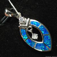 Front view of marquise-shaped sterling silver pendant with blue opalite inlay and two clear gemstones.