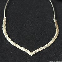 Full view of the sterling silver necklace showing the twisted and textured V-shaped front design against a black background.