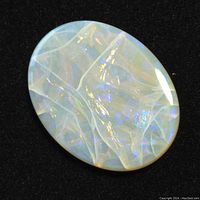 Close-up image of oval Australian opal gemstone on black background showing its translucent milky white body with internal blue and orange play of colors.