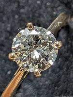 Close-up of round brilliant diamond in four-prong yellow gold setting