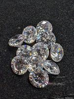 Loose round brilliant cut cubic zirconia stones totaling 20 carats on a black background.