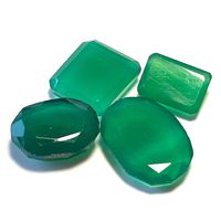Four green agate faceted gemstones arranged together on a white surface, showing their shapes and colors.