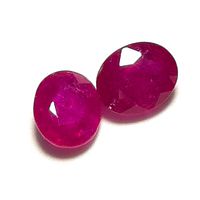 Two oval-cut ruby gemstones placed side by side on a white background showing their color and facets.