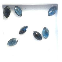 Top-down view of seven marquise cut sapphires in a white display box showing deep blue facets.