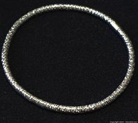 Full view of the circular stretchable sterling silver bracelet on a black background
