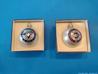 Photo of two boxed 1992 Blue Jays Christmas tree ornaments, one showing team logo and the other showing World Series logo, laid out on a blue surface.