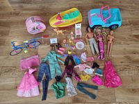 Overview photo showing Barbie dolls, clothing, doll accessories, and toys arranged on floor