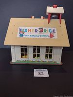 Front view of the Fisher Price Play Family School toy house showing the yellow roof with decal and window details below.