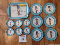 Full set of 11 Holly Hobbie metal plates and tray arranged on wooden surface displaying all items in lot