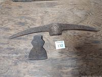 Top down photo of rusty pick axe head and rusty axe head on wooden floor, showing condition and size