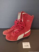 Side angle view of the red suede PUMA shoes showing profile, laces, and white stripe on side.