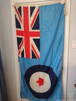Full view of the RCAF flag hanging vertically showing Union Jack and the blue field with roundel and maple leaf