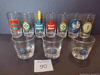 Front view of 8 tall glasses and 3 short glasses with various RCAF emblems and logos.