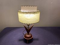 Full view of lamp illuminated showing two-tier fiberglass shade and tripod base