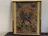 Full view of the framed thangka painting showing the central wrathful deity surrounded by a fiery halo and four smaller wrathful figures at corners.