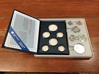 Full uncirculated coin set with six coins displayed in presentation case alongside certificate of authenticity.