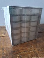 Sealed cube-shaped box showing 6 rows of small white tea lights stacked inside clear plastic holders.