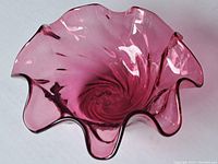 Top-down view of the cranberry glass bowl showing the swirl pattern and ruffled edge clearly.