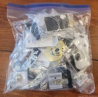 Clear resealable plastic bag containing approximately 40 pairs of various new earrings for pierced ears. Multiple styles visible including glittery, metallic finish, textured, and rhinestone-adorned designs all in cards or plastic packaging.