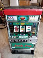 Front view of electric slot machine showing reels, symbols, payout table, and control buttons.