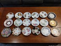 Overhead view of 18 assorted tea saucers with various floral and patterned designs.