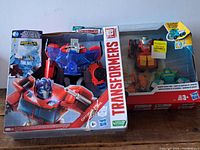 Boxed set of Transformers action figures featuring Optimus Prime and three other robots in red, orange, and green.